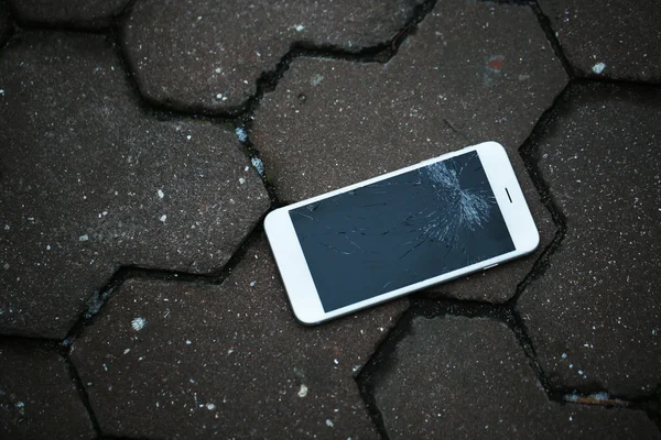 Broken phone on asphalt