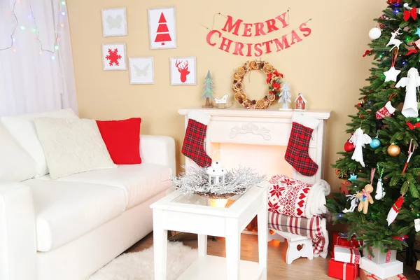 Beautiful Christmas interior with sofa, decorative fireplace and fir tree