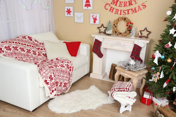 Beautiful Christmas interior with sofa, decorative fireplace and fir tree