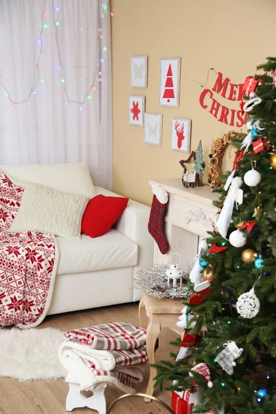 Beautiful Christmas interior with sofa, decorative fireplace and fir tree