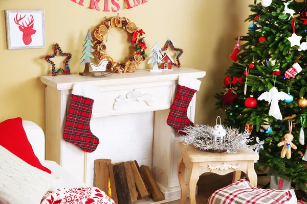 Beautiful Christmas interior with sofa, decorative fireplace and fir tree