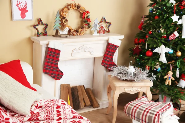 Beautiful Christmas interior with sofa, decorative fireplace and fir tree