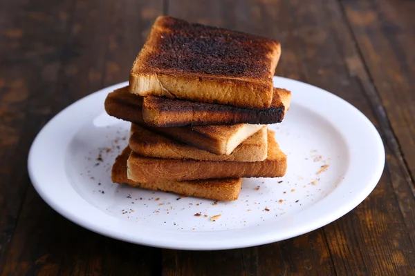 Burnt toast bread on plate, on wooden table 