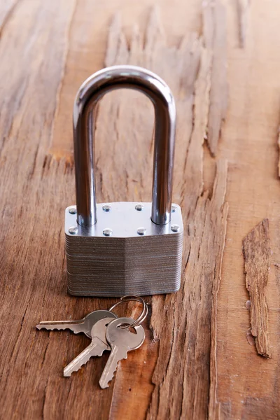 Padlock with keys on wooden background