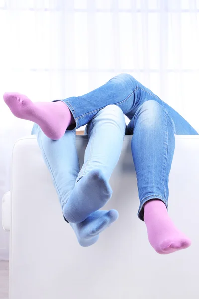 Male and female legs on sofa close-up