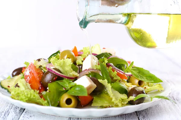 Greek salad dressing with olive oil on wooden surface and light background