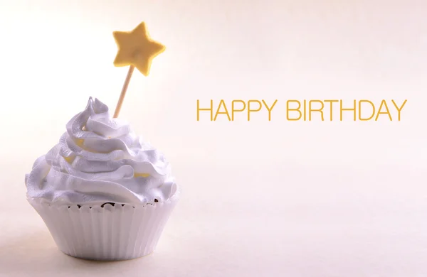 Delicious cupcake with star on stick and Happy Birthday text on light background