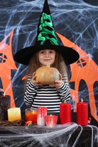 Little girl Witch in hat on Halloween decorations background