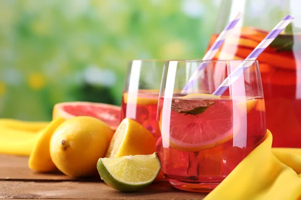 Pink lemonade in glasses and pitcher on table on natural background
