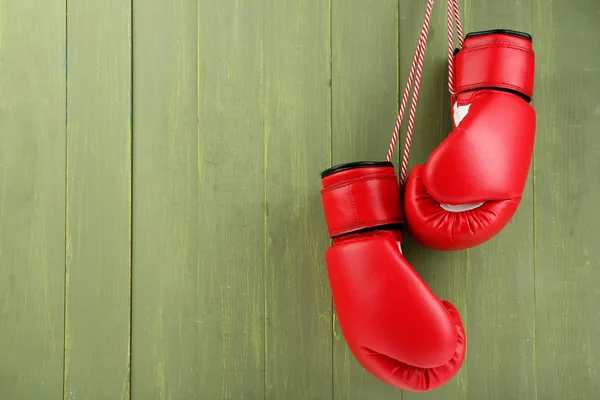 Pair of boxing gloves on color wooden background