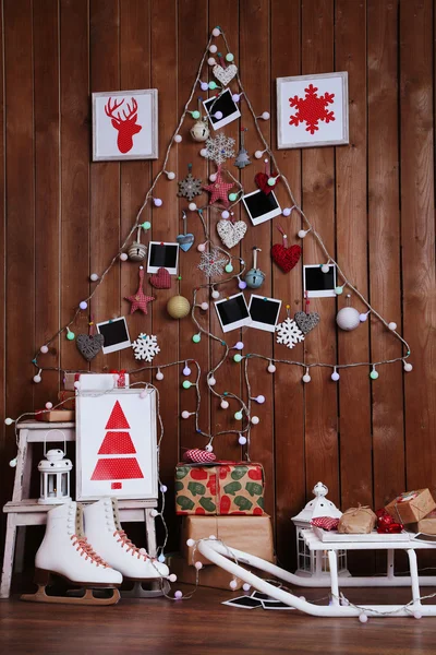 Garland in shape of Christmas tree on wooden wall background, gift boxes and lantern. Christmas atmosphere concept
