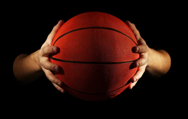 Basketball player holding ball, on dark background