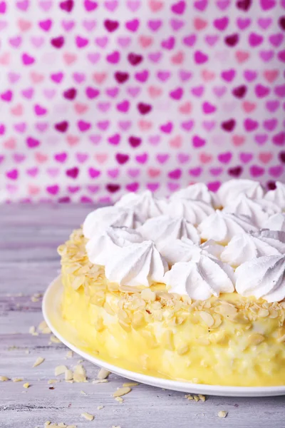 Tasty homemade meringue cake on wooden table, on pink background