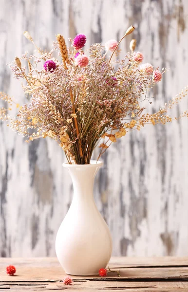 Bouquet of dried flowers in vase on bright background