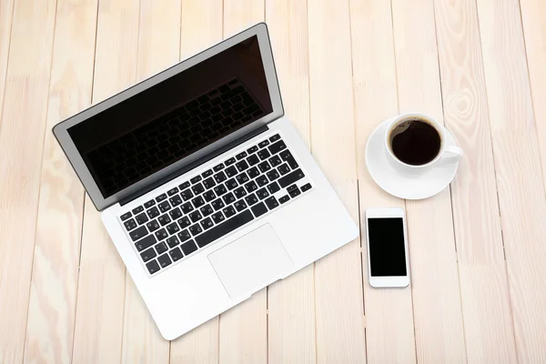 Open notebook, digital tablet, diary, smart phone and a cup of coffee on wooden background, top view