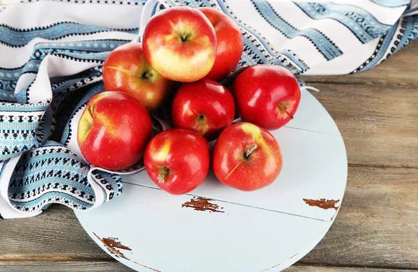 Heap of apples on board with dish cloth on wooden table background