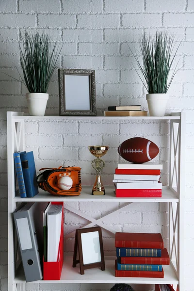 Bookshelves with books and decorative objects on brick wall background