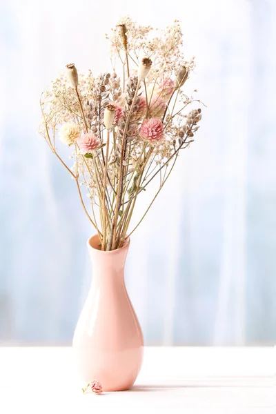 Bouquet of dried flowers in vase on light background