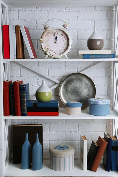 Bookshelves with books and decorative objects on brick wall background