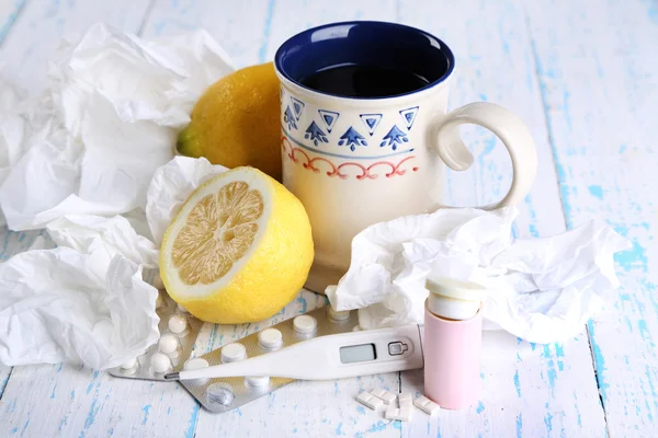 Hot tea for colds, pills and handkerchiefs on table close-up