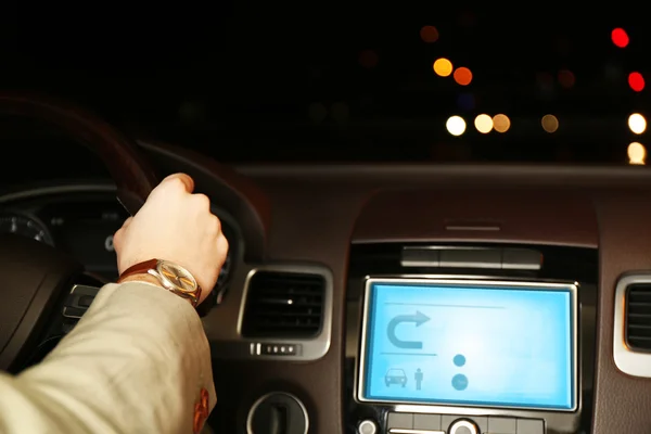 Man driving his modern car at night in city, close-up