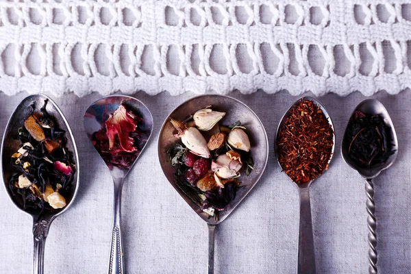 Tea in metal spoons on lace fabric background