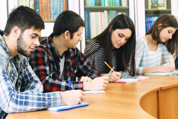 Group of students sitting at table in library