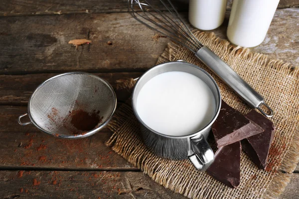 Metal mug and glass bottles of milk