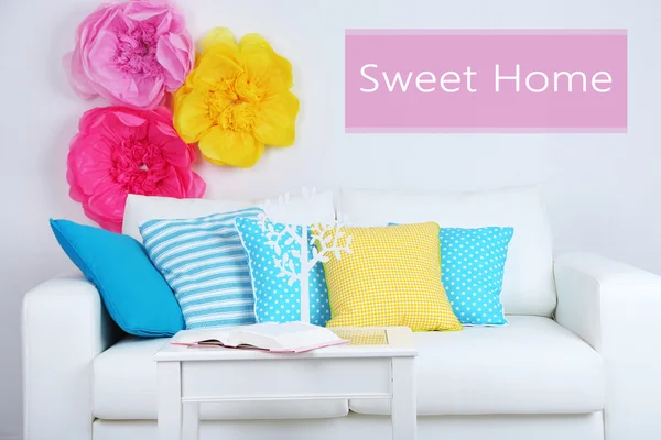 White sofa with colorful pillows in room on wall background, Sweet Home concept