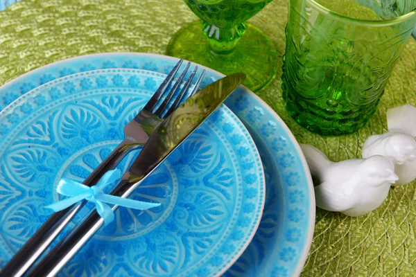 Empty colorful plate, glasses and silverware set on wooden table