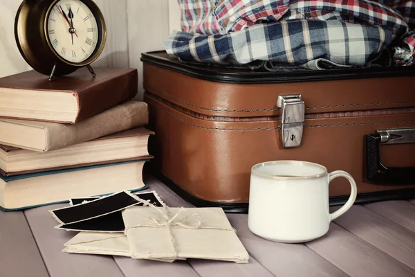 Vintage suitcase with clothes and books on wooden background