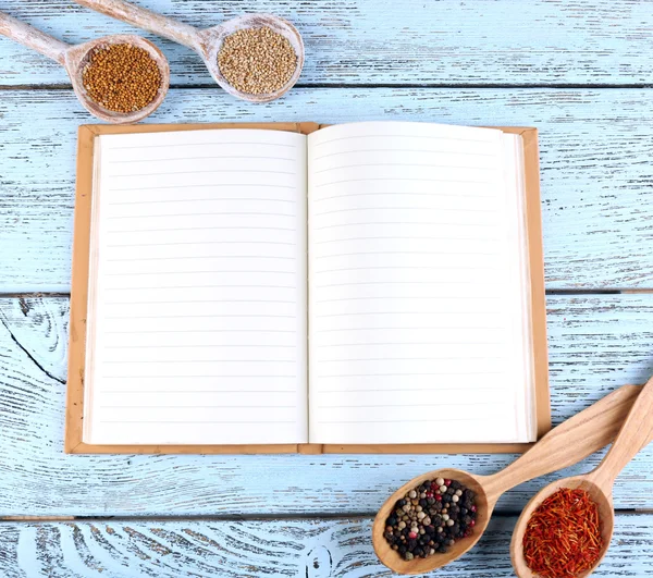 Spices with recipe book on color wooden table background