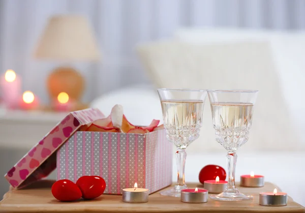 Champagne glasses, gift box and rose petals for celebrating Valentines Day