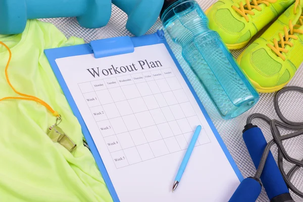 Workout plan and sports equipment top view close-up