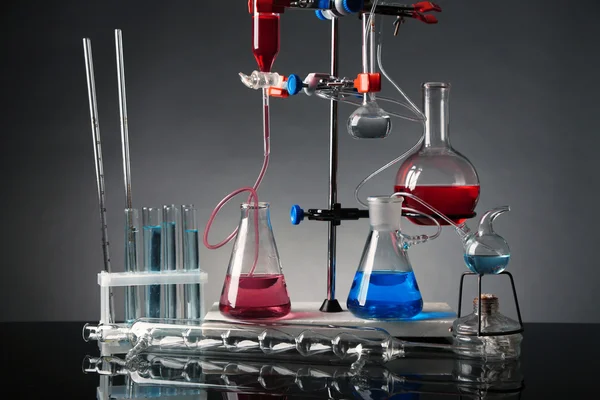 Fixed laboratory glassware on support on dark colorful background