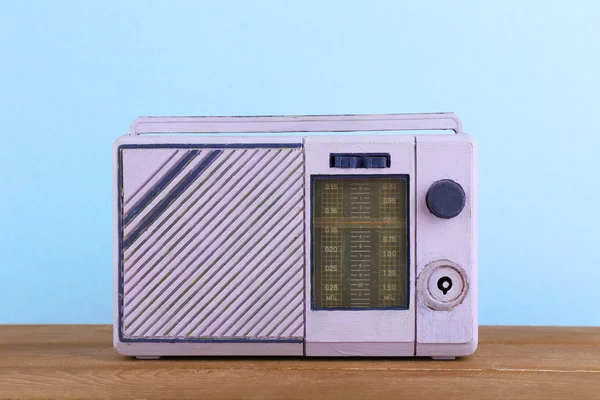 Retro radio on wooden table on light colorful background