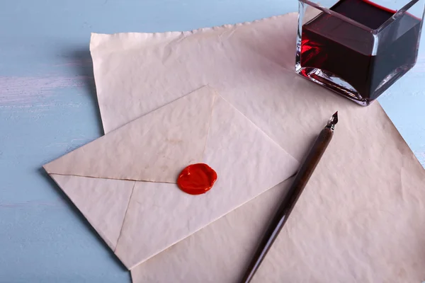 Envelope with pen and ink on wooden background