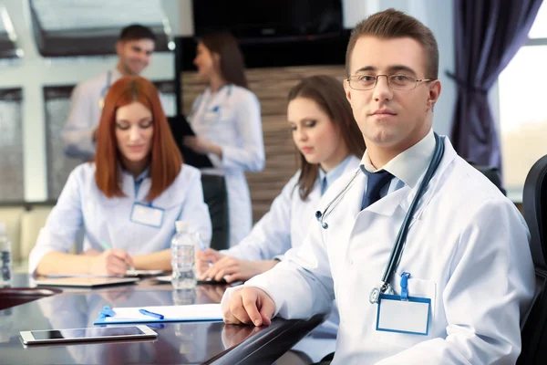 Attractive male doctor with team in conference room