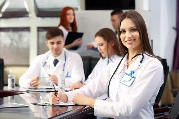 Beautiful young doctor with team in conference room