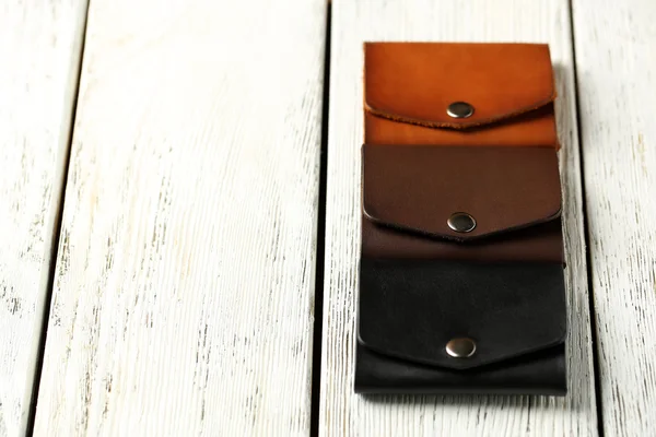 Three hand made leather man wallets on white wooden background