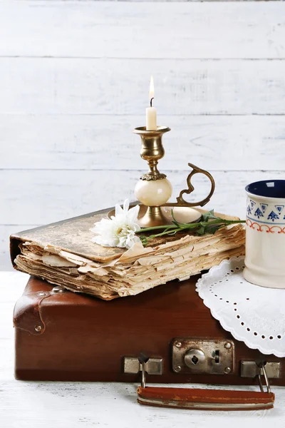 Old wooden suitcase with old books and flowers on wooden background