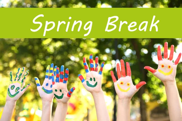 Spring break concept. Smiling colorful hands on nature background