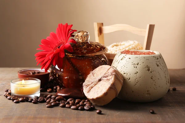 Composition of spa treatment, flowers and coffee beans on wooden table, on light color background