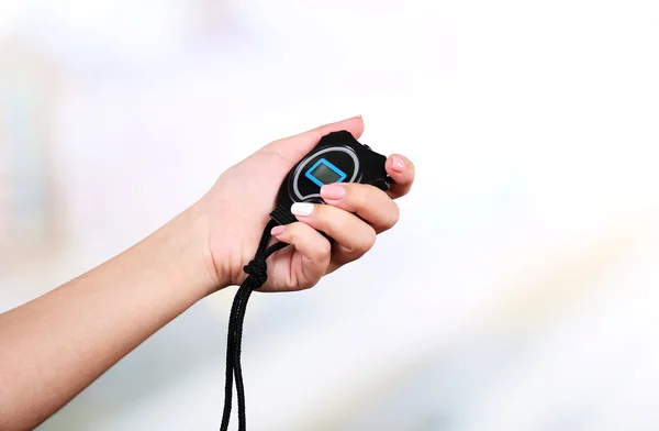 Electronic sport timer in  female hand on bright blurred background