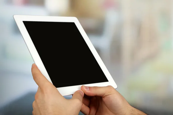 Hands using tablet PC on light blurred background