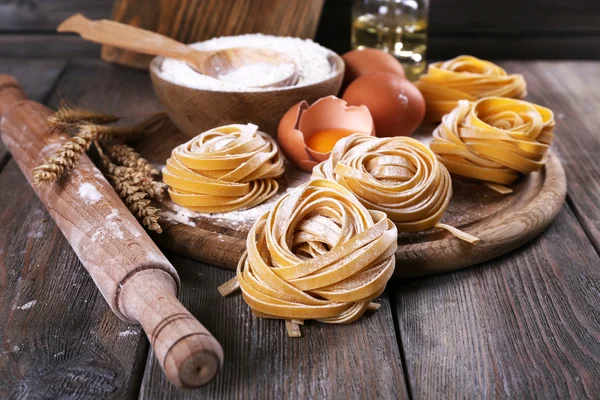 Raw homemade pasta and ingredients for pasta on wooden background