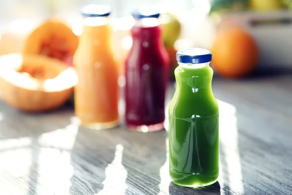 Bottles of juice with fruits and vegetables  on windowsill close up
