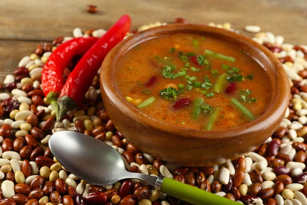 Bean soup in bowl and raw beans on wooden table background
