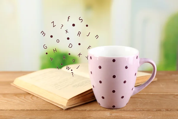 Open book with flying letters on table on bright background