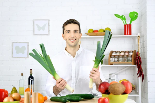 Man at table with different products in kitchen on white wall background